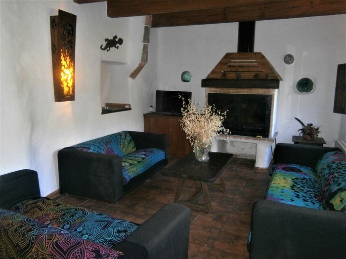 Salón con chimenea, TV, tres sofás y decoración artesanía.